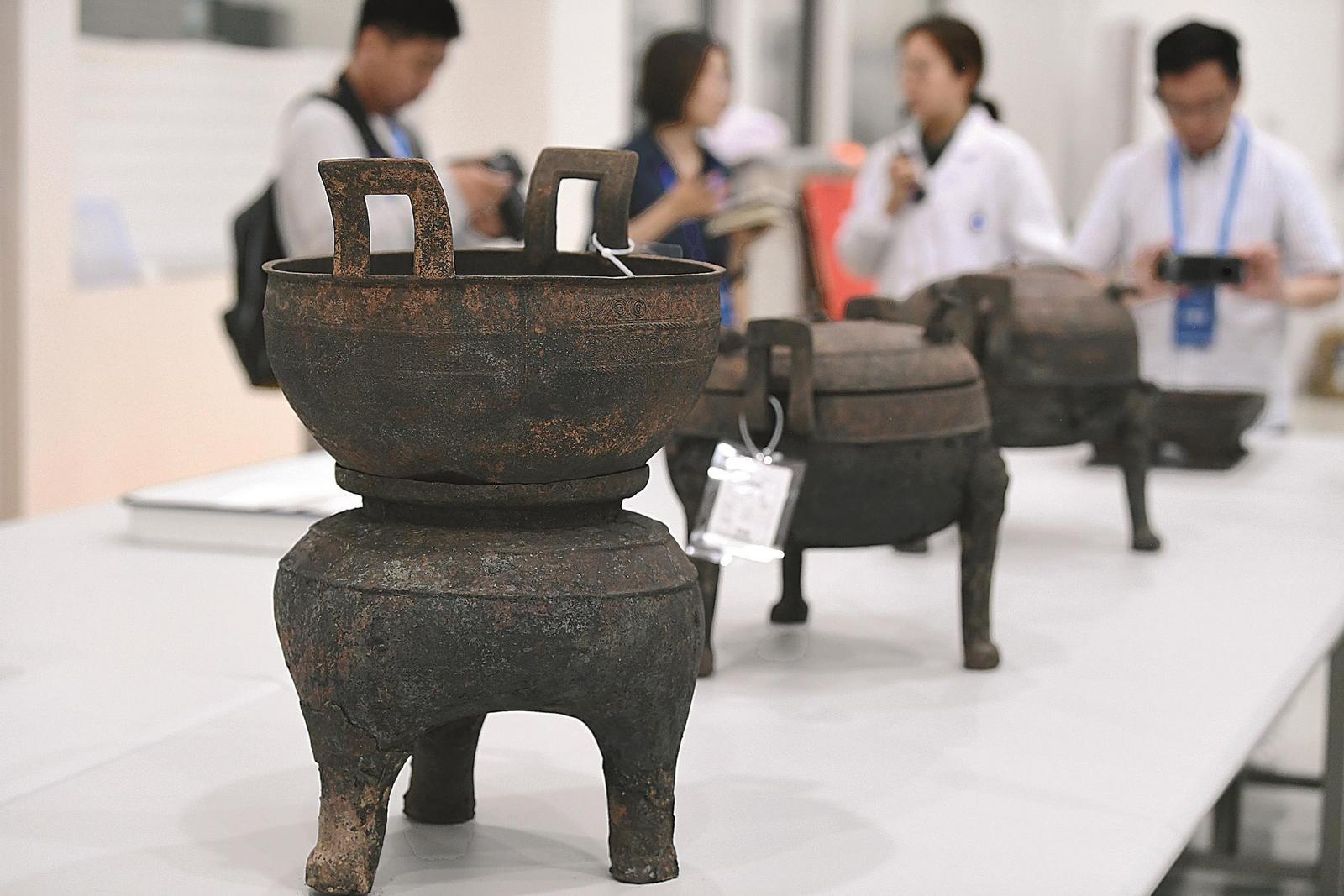 在淮南武王墩墓发掘现场,考古人员向记者介绍出土的青铜器。本报记者 徐旻昊 摄