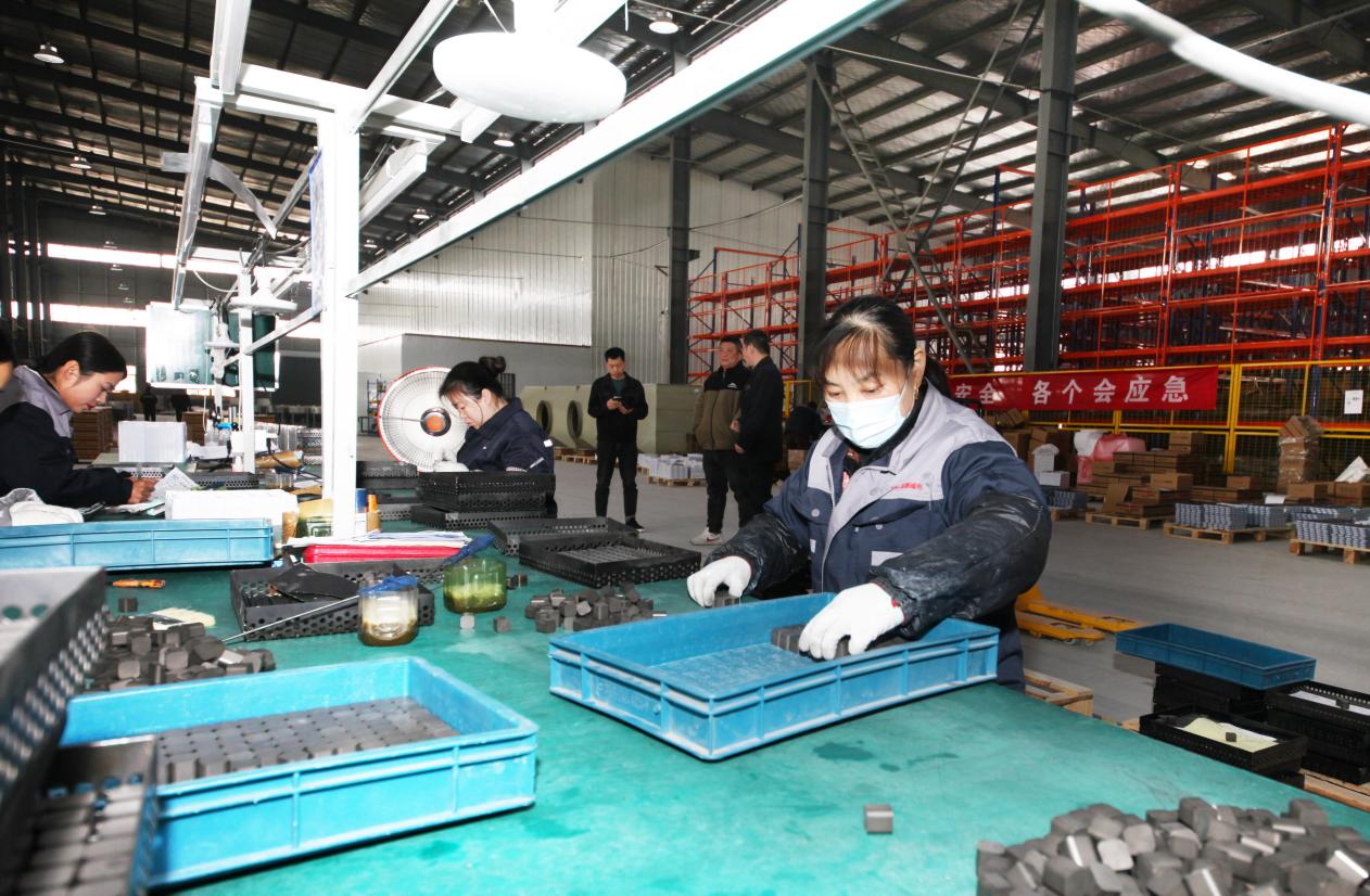 工人们忙碌的身影穿梭其间，正在生产磁芯订单产品。